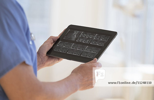 Mann im Kittel betrachtet Ultraschallergebnisse auf einem Tablet