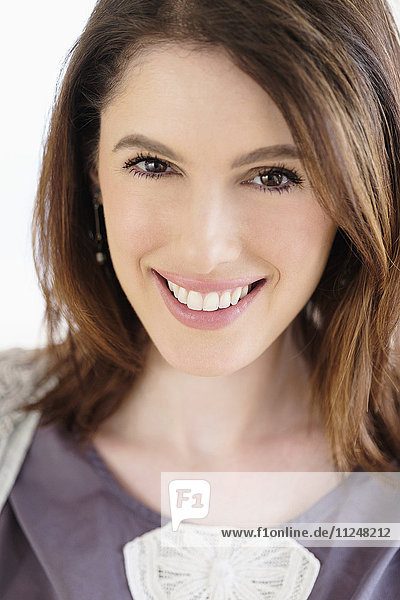 Studio shot portrait of smiling woman with brown hair