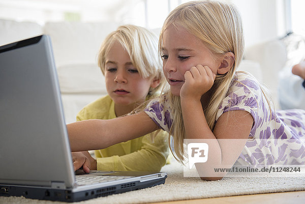 Junge (4-5) und Mädchen (6-7) benutzen Laptop