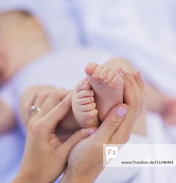 Mother holding baby boy 's (6-11 months) feet