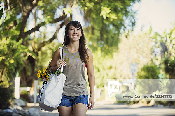 Junge Frau mit Einkaufstasche beim Gehen