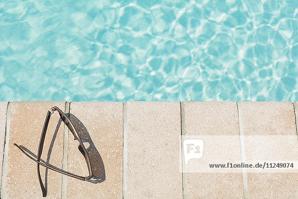 Sunglasses on brick ledge by pool