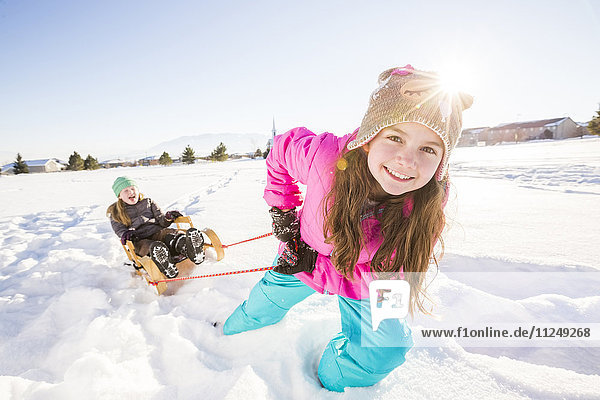 Children (8-9  10-11) playing with sled in snow