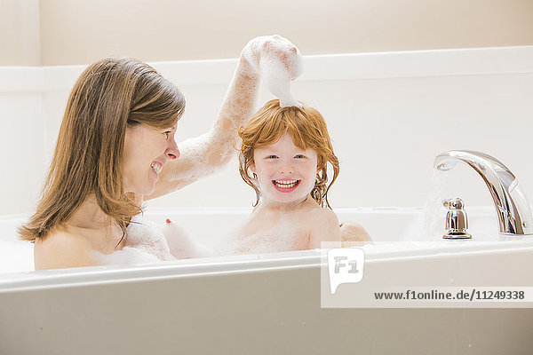 Mother and daughter (4-5) having bubble bath