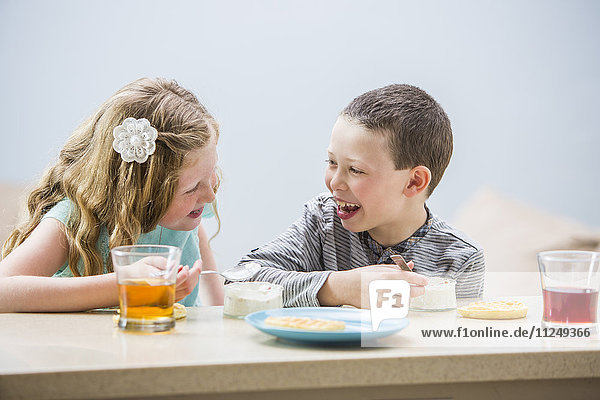 Lächelnde Kinder (6-7  8-9) essen Pudding am Tisch