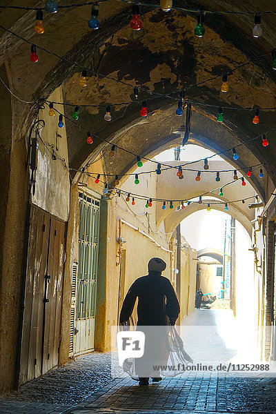 Mullah hurrying down typical vaulted alleyway  Yazd  Iran  Middle East