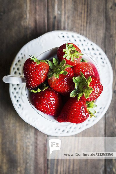 Frische Erdbeeren in einer Teetasse auf Holztisch