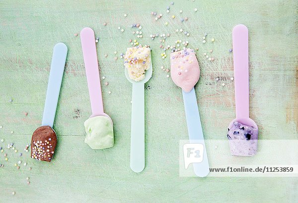 Eislöffel mit verschiedenen Eissorten: Vanille, Erdbeere, Schokolade, Heidelbeere und Minze mit Zuckerperlen
