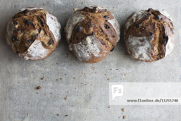 Three loaves of crusty bread made from chestnut flour with raisins and hazelnuts