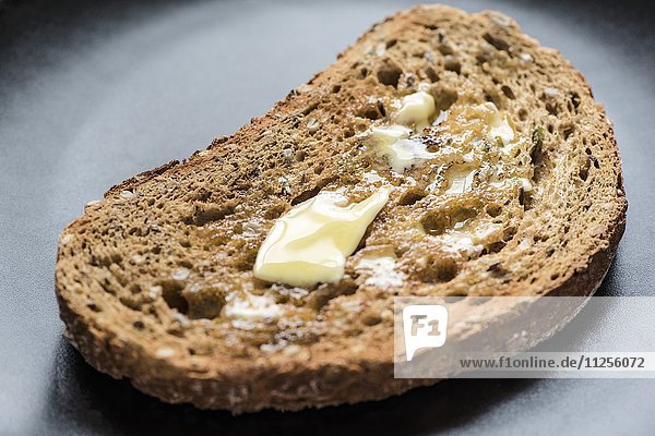 Eine Scheibe Vollkorntoast mit schmelzender Butter