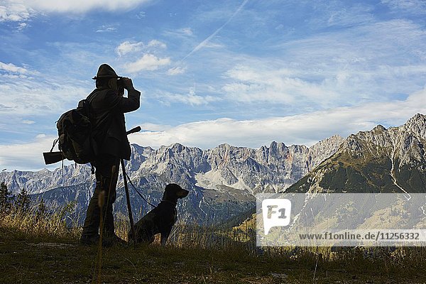 Jäger mit Jagdhund vor Bergkulisse