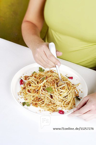 Frau isst Spaghetti mit Sardellen