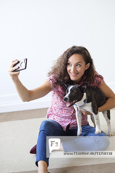 Frau hält Hund und macht Selfie