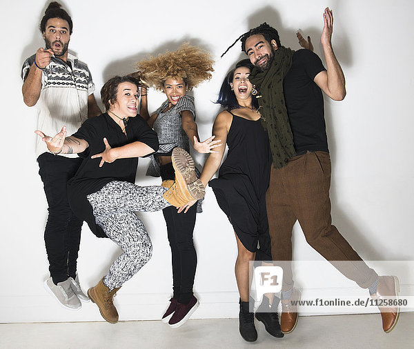 Porträt einer Gruppe von glücklichen Freunden vor einer weißen Wand beim Springen