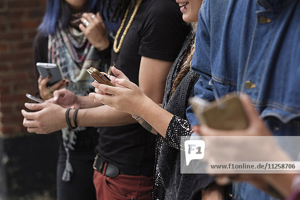 Young people standing in row using smartphones