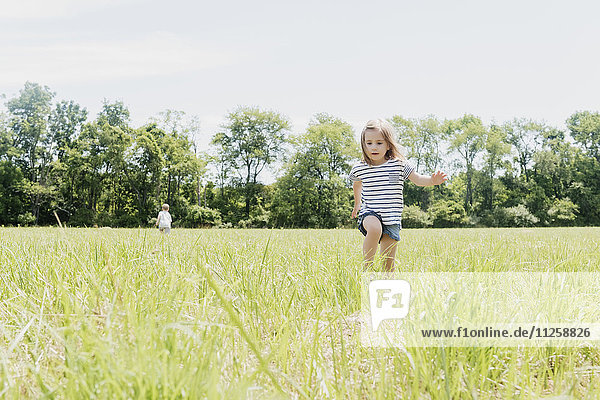 USA  Pennsylvania  Washington Crossing  Girl (2-3) and boy (4-5) walking on green field