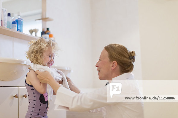 Mother helping daughter (4-5) get dressed