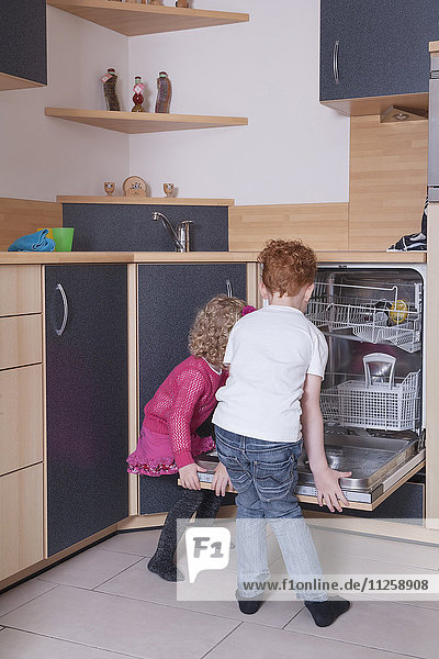 Girl (4-5) and boy (8-9) loading dishwasher