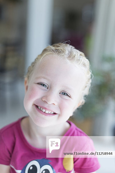 Porträt eines blonden Mädchens (4-5)  das in die Kamera schaut und lächelt