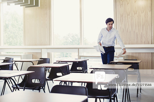 Hochschulprofessor beim Sammeln von Tests auf Tischen im Klassenzimmer