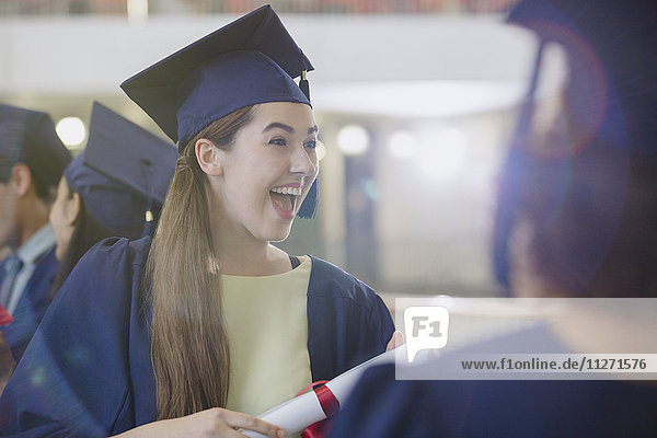 Enthusiastic female college graduate in cap and gown