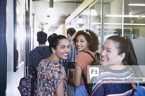 Portrait smiling female college students walking in corridor