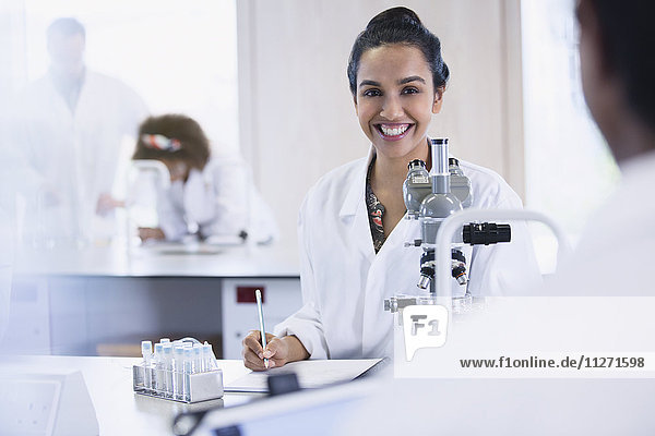 Lächelnde Studentin führt wissenschaftliches Experiment im Klassenzimmer des Wissenschaftslabors durch