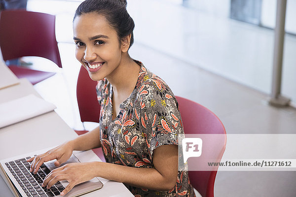 Portrait smiling college student using laptop