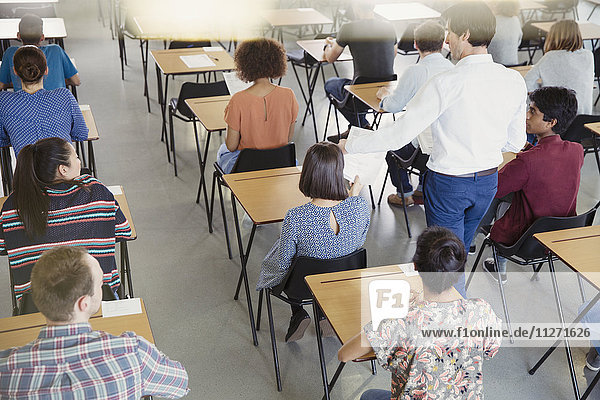 Professor beim Sammeln von Tests von Schülern im Klassenzimmer