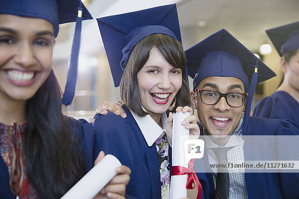 Porträt begeisterte Hochschulabsolventen in Mütze und Mantel posierend mit Diplom