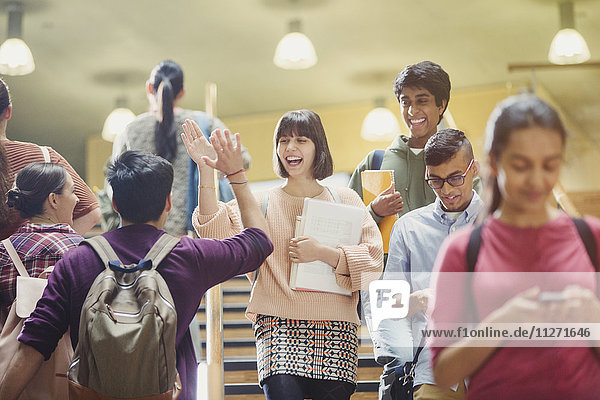 Enthusiastic college students high-fiving in stairway