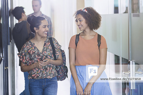 Smiling female college students walking in corridor