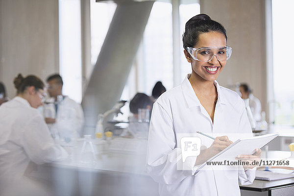 Portrait smiling female college student taking notes in science laboratory classroom