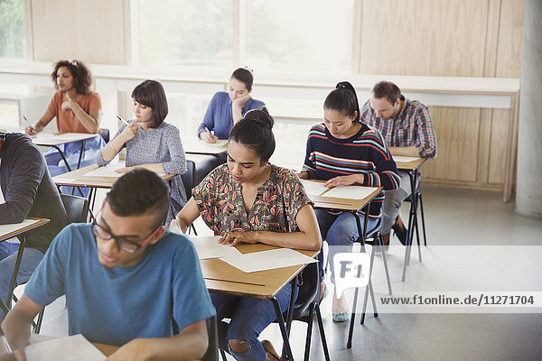 College students taking test at desks in classroom