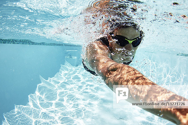 Männlicher Schwimmer  der im Schwimmbad unter Wasser schwimmt.
