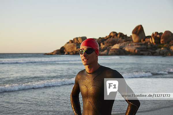 Male triathlete swimmer in wet suit on ocean beach