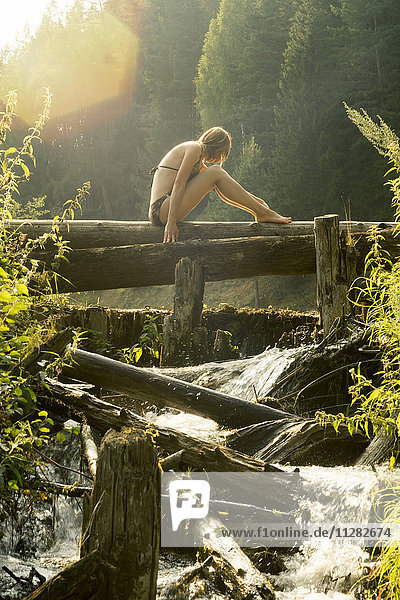 Caucasian woman sitting on log over waterfalls