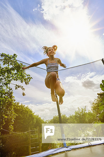 Niedriger Winkel Blick auf kaukasischen Mädchen springen auf Trampolin