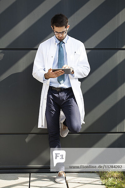 Arzt mit Brille und digitalem Tablet im Freien
