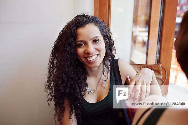 Lächelnde schwarze Frau trinkt Smoothie in einem Café