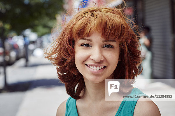 Hispanic woman smiling on city sidewalk