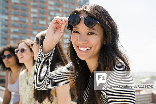 Smiling woman lifting sunglasses outdoors