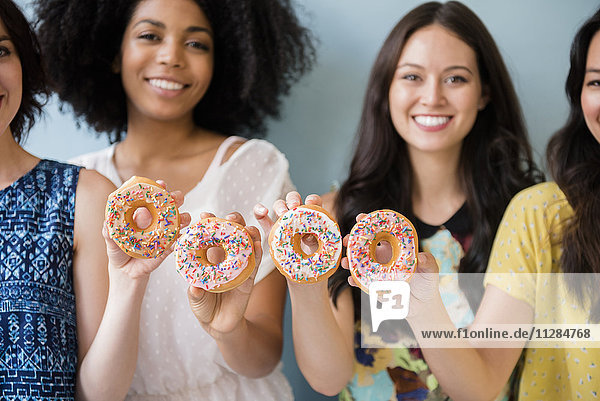 Porträt einer lächelnden Frau  die mit Donuts posiert