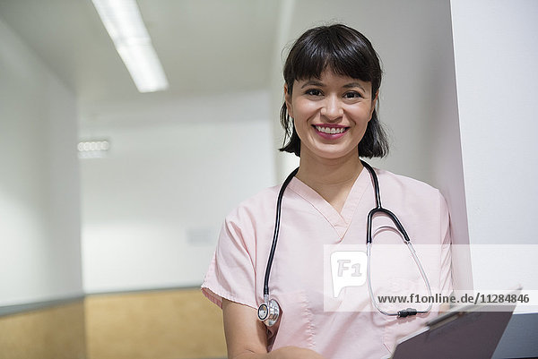 Lächelnde hispanische Krankenschwester mit Klemmbrett