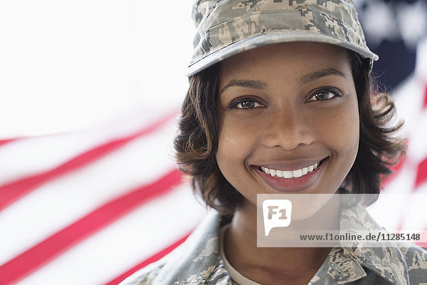 Porträt eines lächelnden gemischtrassigen Soldaten in der Nähe der amerikanischen Flagge
