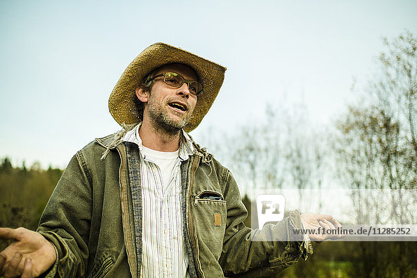 Kaukasischer Bauer mit Cowboyhut  der im Freien spricht und gestikuliert