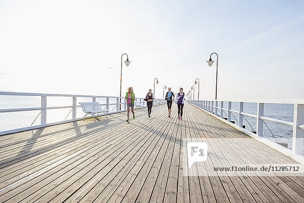 Group of women in sports clothing running on jetty
