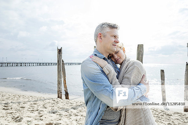 Man on beach embracing girlfriend