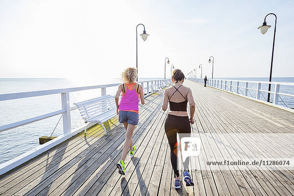 Two women jogging along a jetty