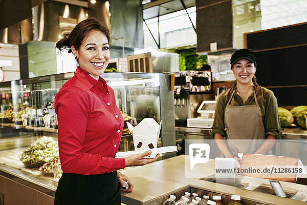 Businesswoman holding carton of food in food court